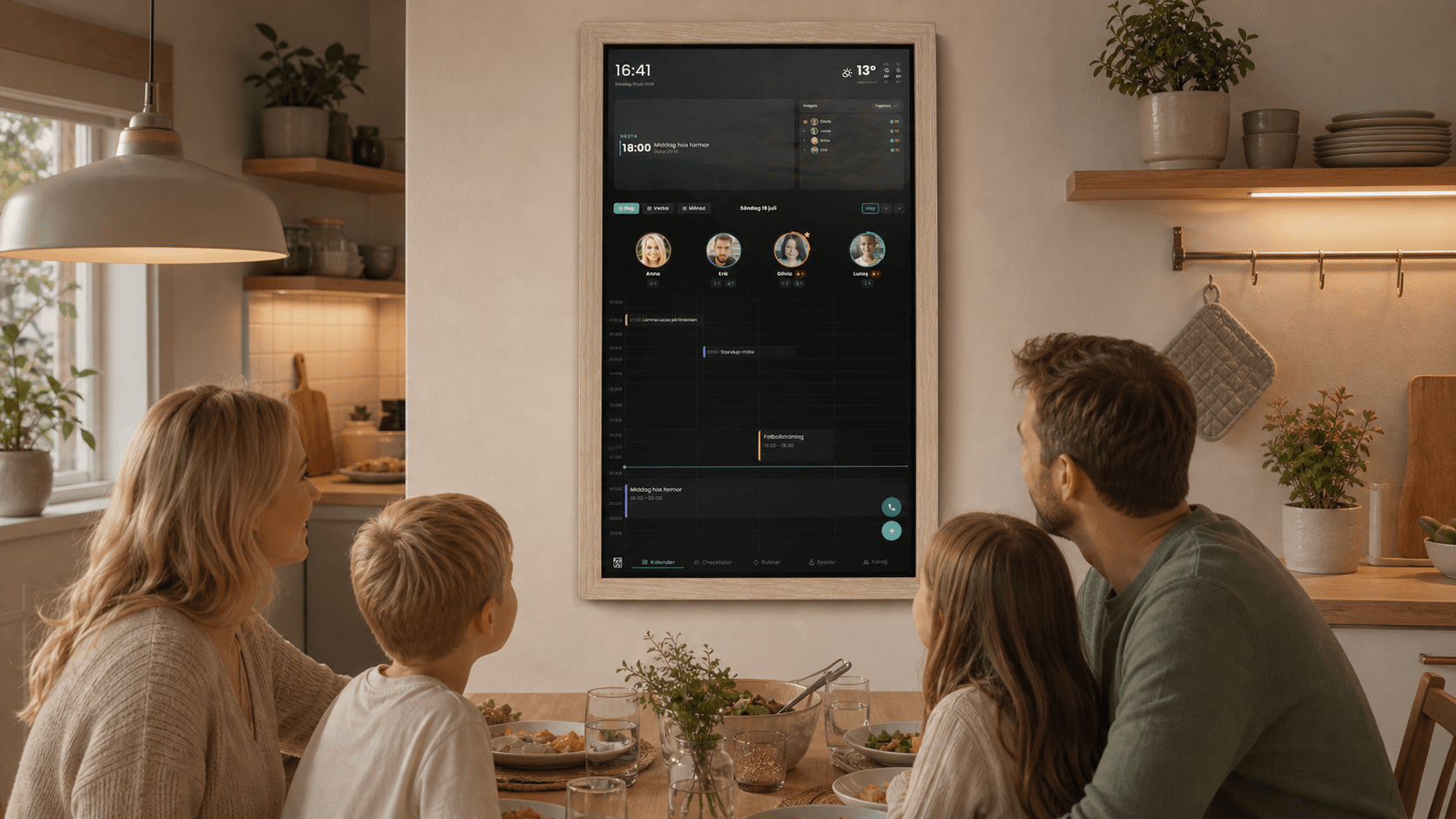Familj samlad i köket runt ZEKA digital familjekalender på väggen